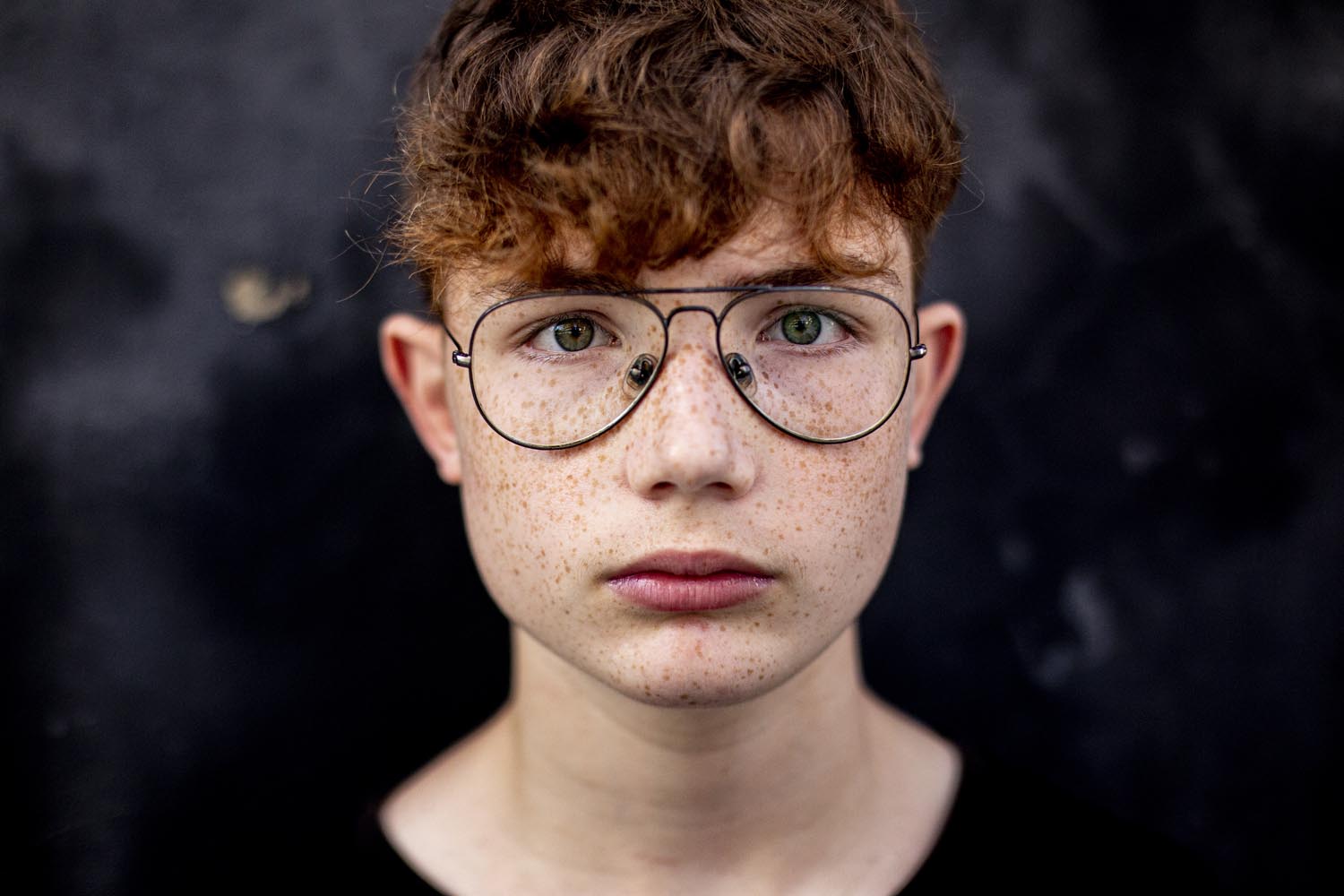 Portrait of red-haired teen boy with freckles and eyeglasses